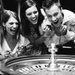 Three friends celebrating by roulette table, laughing